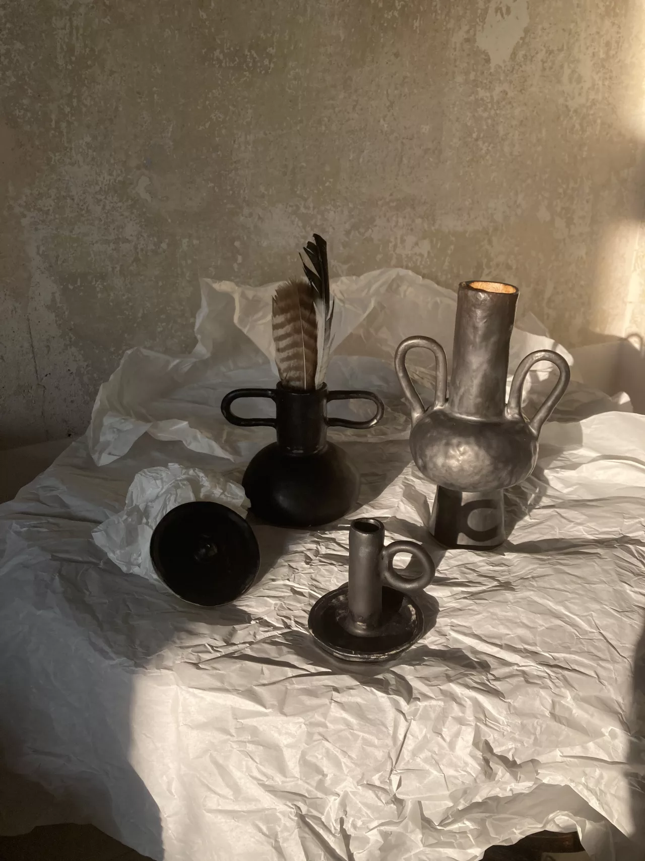 Czarne ceramiczne wazony i świecznik w promieniach popołudniowego światła